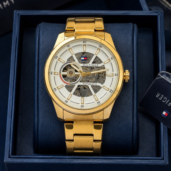Gold automatic men's watch with 43mm round skeleton dial, stainless steel bracelet, transparent front and back, and self-winding mechanical movement.
