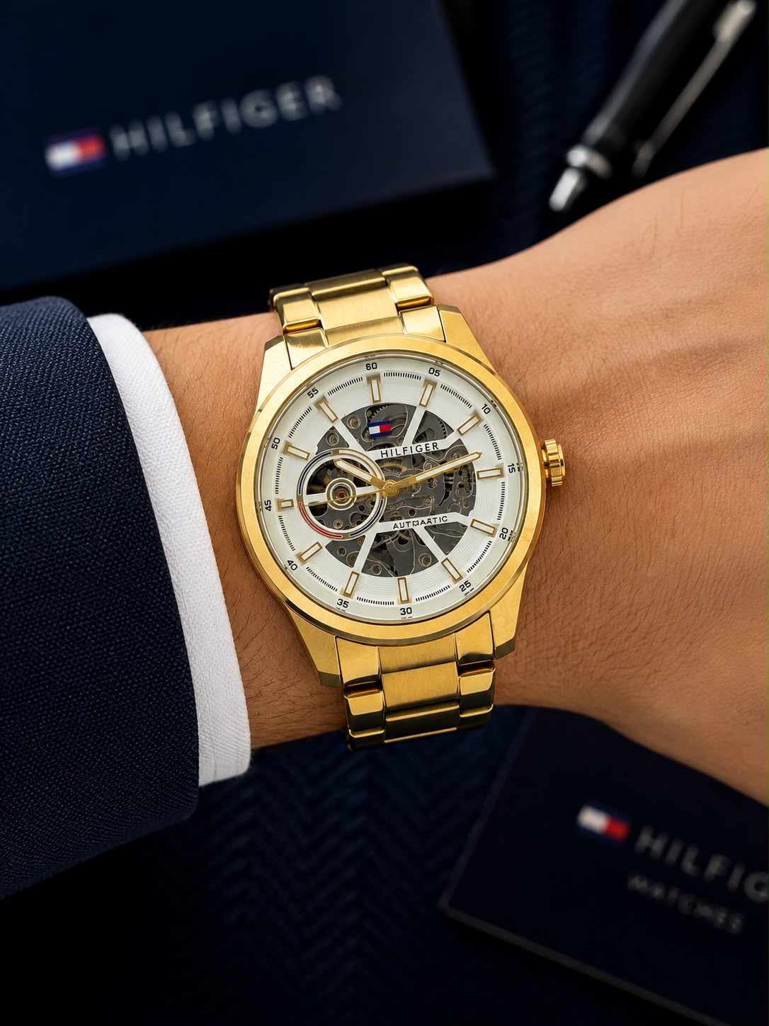 Gold automatic men's watch with 43mm round skeleton dial, stainless steel bracelet, transparent front and back, and self-winding mechanical movement.