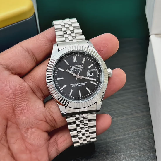 black dial silver stainless steel watch with fluted bezel, magnified date display and multi-link bracelet